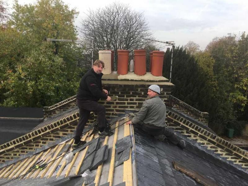D&R Roofing Experts are working on the roof of a house.