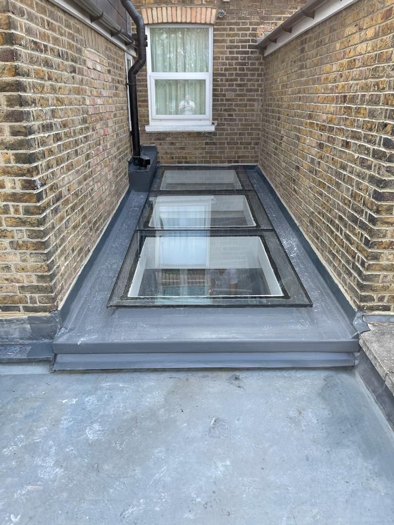 Newly installed flat roof with multiple large skylights by a roofer in Wimbledon.