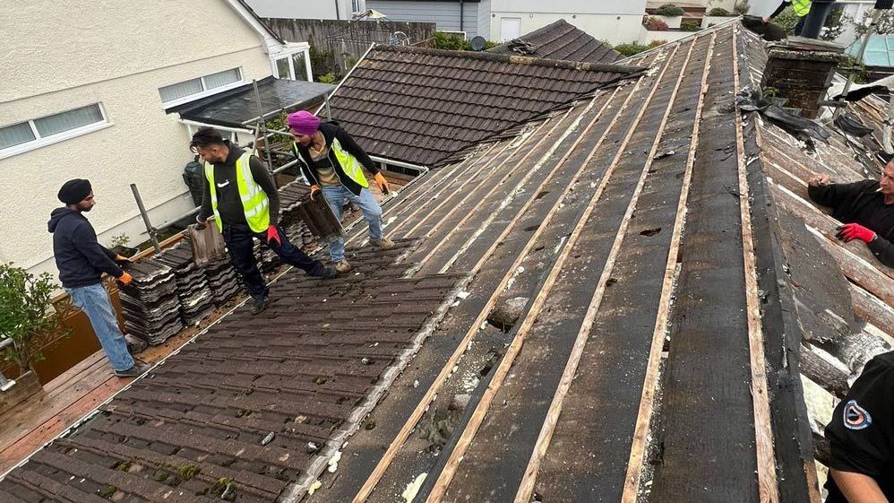 Roofers in Wimbledon removing old tiles for a roof replacement.