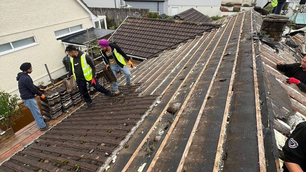 Roofers in Wimbledon removing old tiles for a roof replacement.