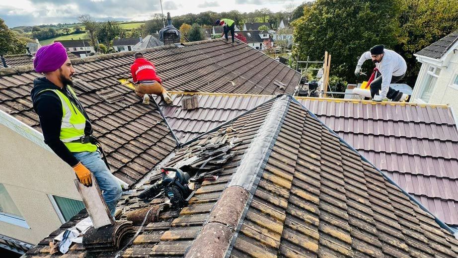 Wimbledon roofer removing old tiles for a new roof installation.
