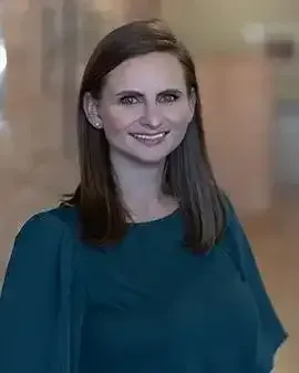 A woman in a blue shirt is smiling for the camera.