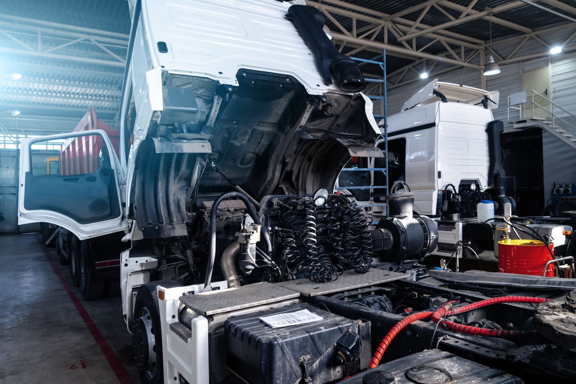 A white semi-truck with its cab tilted forward, revealing its engine A white semi-truck with its cab tilted forward, revealing its engine