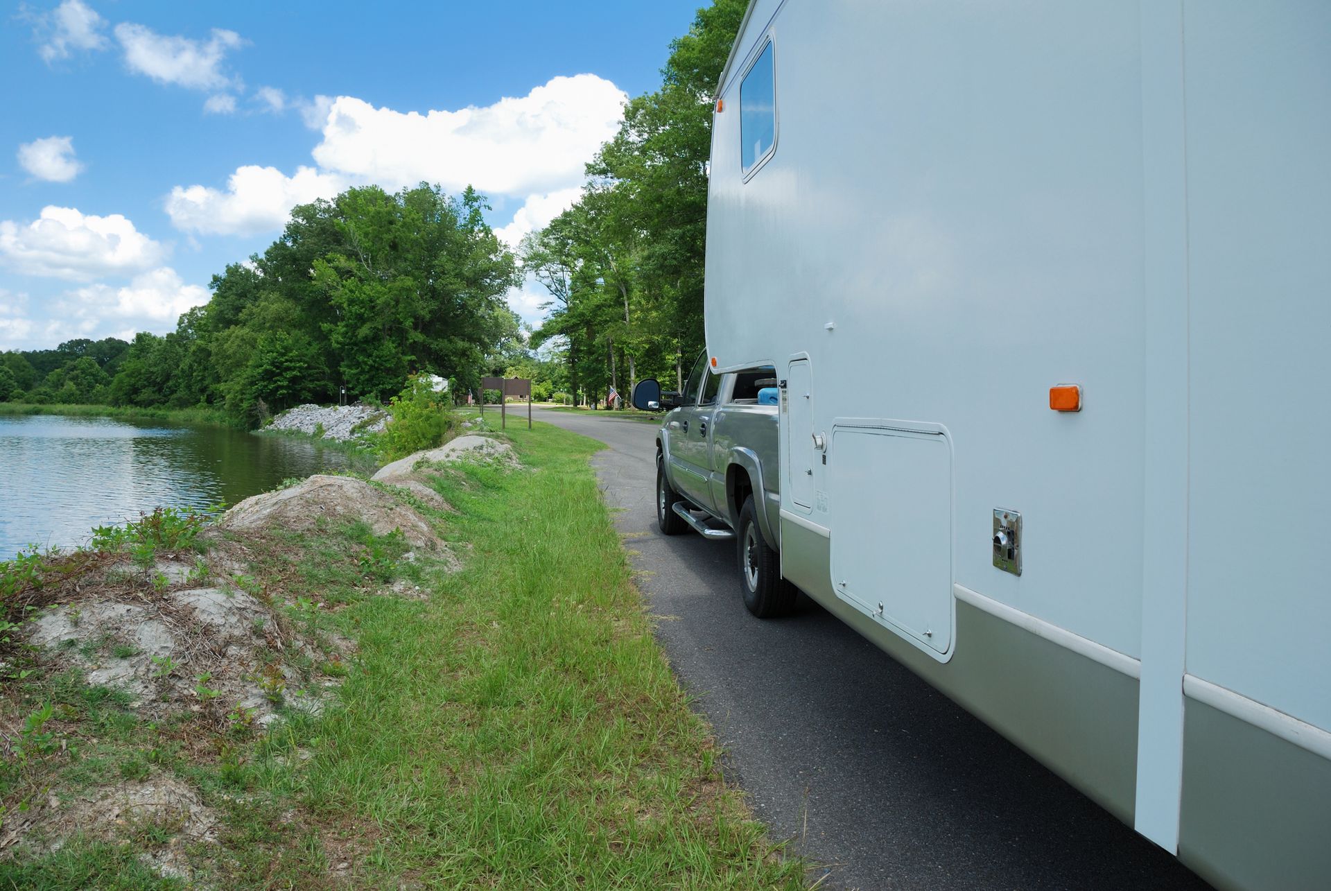Fifth-wheel trailer and truck parked near river. Fifth-wheel trailer and truck parked near river.