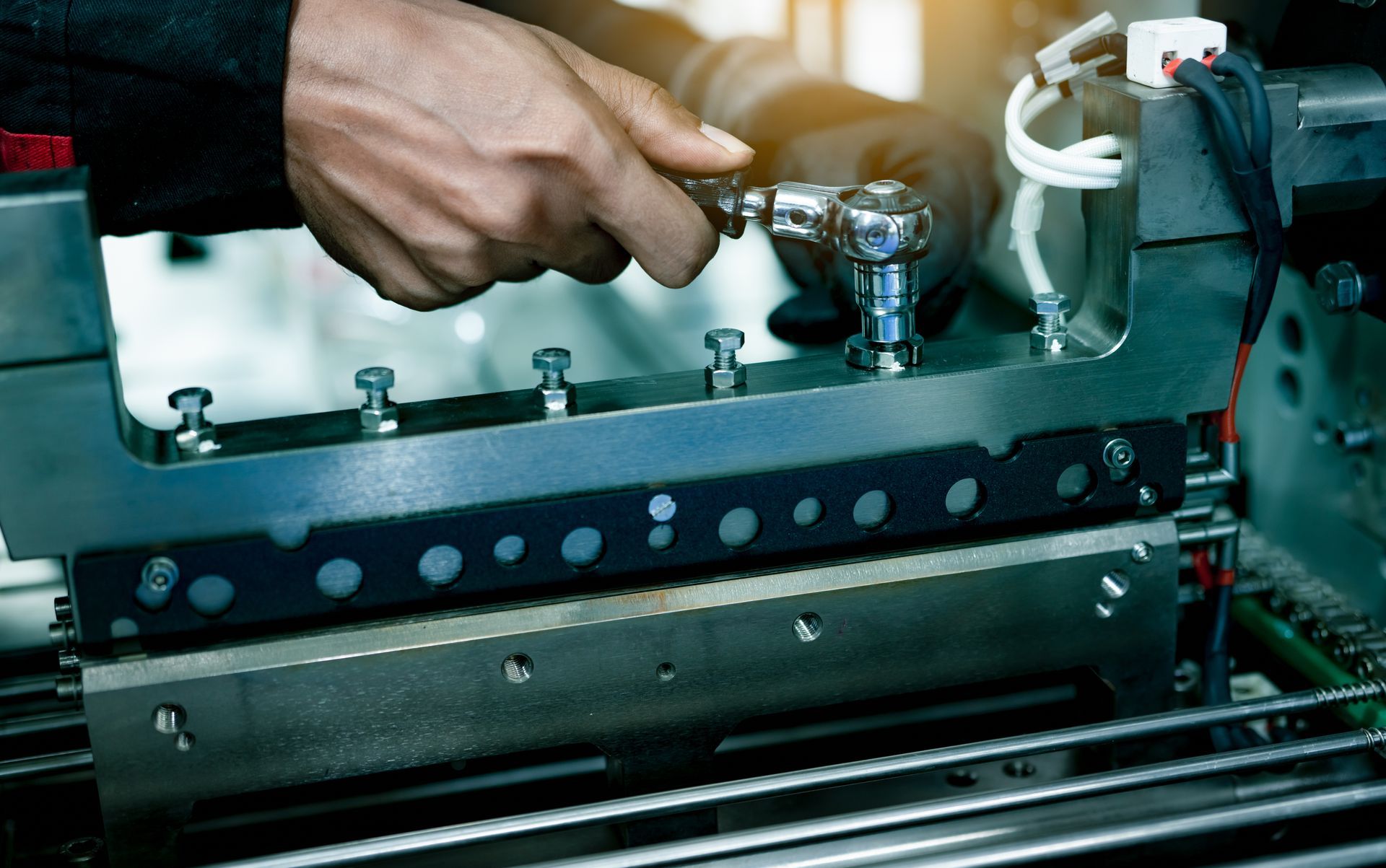 Hand turning a metal valve on an industrial machine with bolts and pipes visible