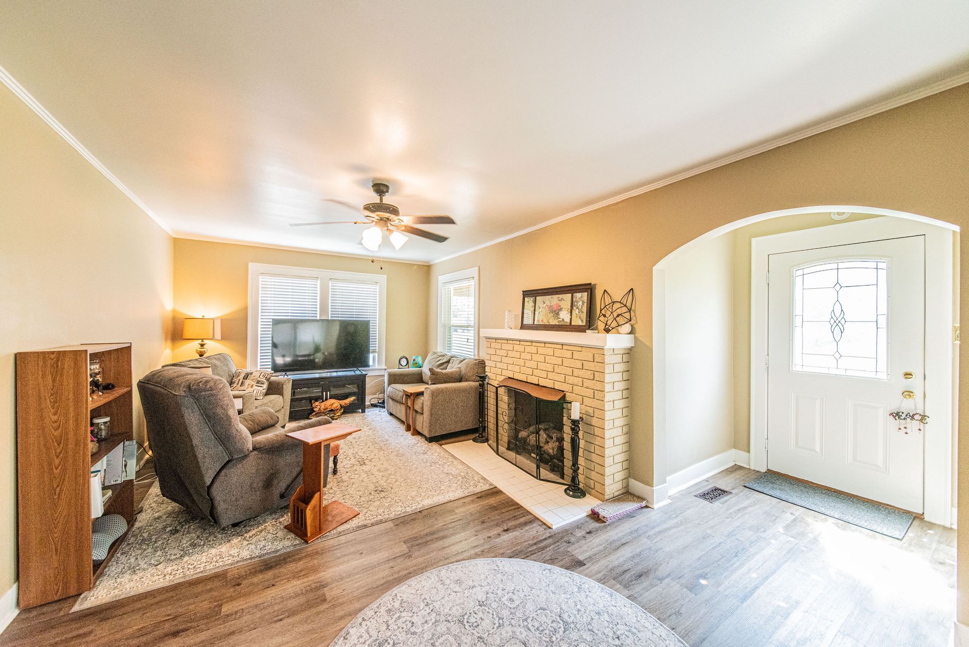 Bright living room with recliner, fireplace, TV, and a front entry door