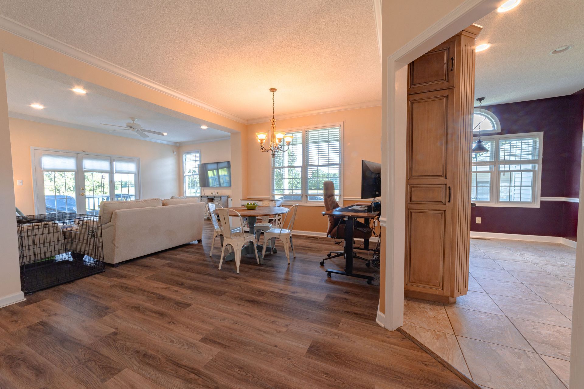 Open living and dining area with wood floors, white sofa, dining table, and a glimpse into a tiled room.
