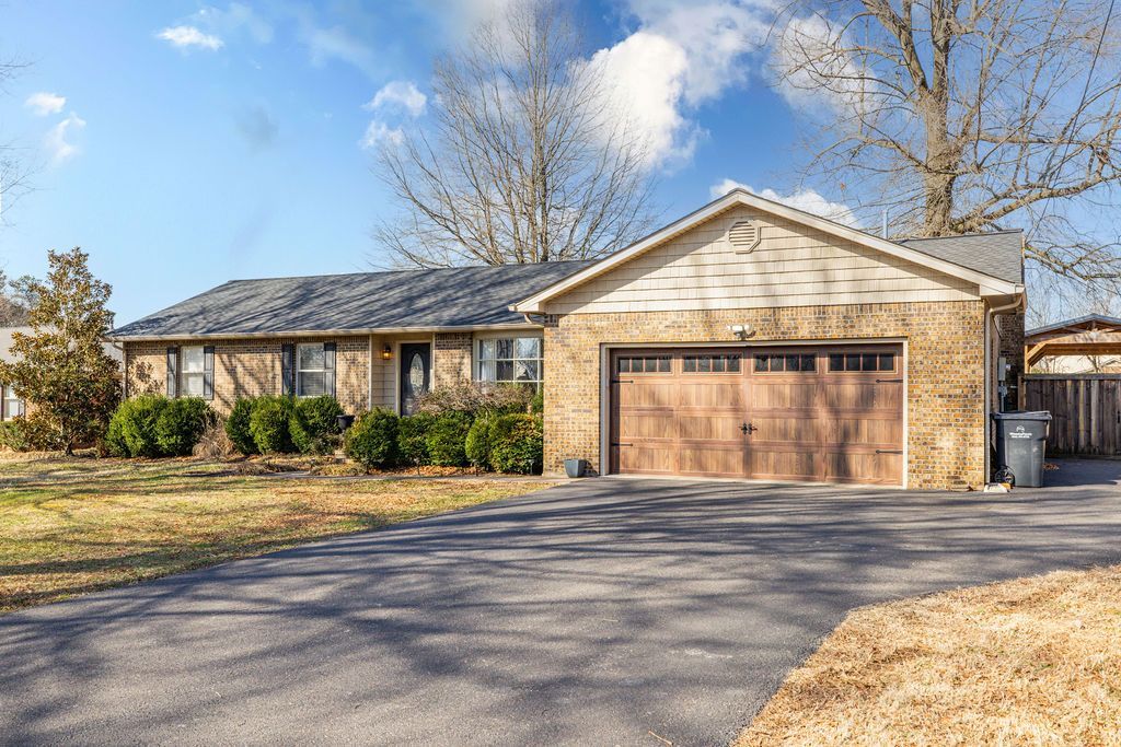 Single-story suburban house with a two-car garage and long driveway on a sunny day