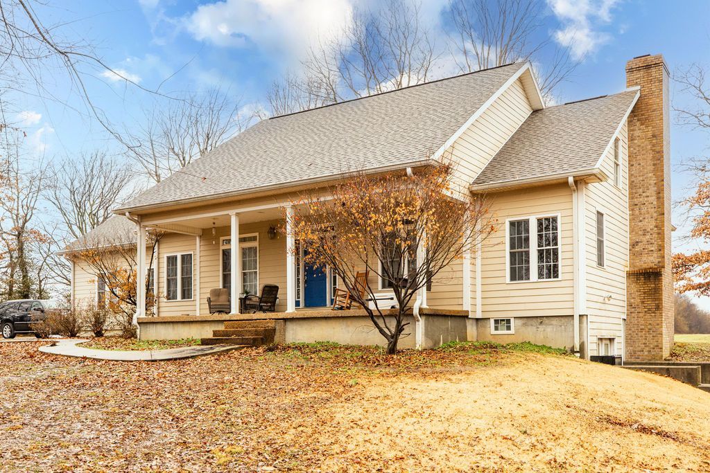 Beige house with porch, white roof, and autumn leaves in the yard