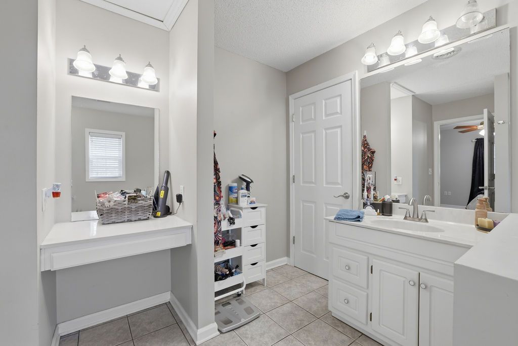 Bright white bathroom with double vanity, large mirror, and tile floor
