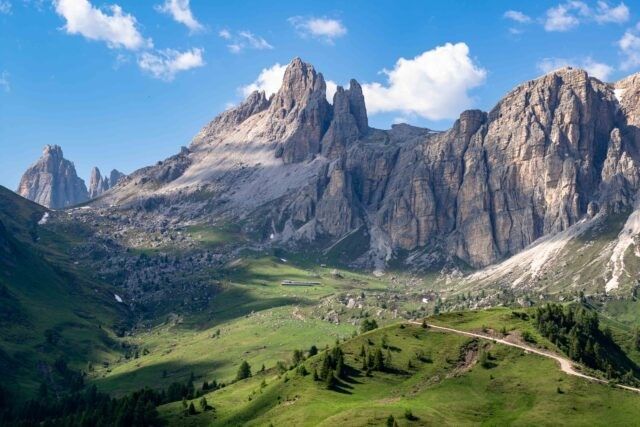 Rocky mountain peaks above a green alpine valley under a blue sky with clouds