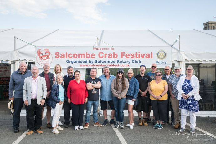 Group of people pose in front of a Salcombe Crab Festival tent.