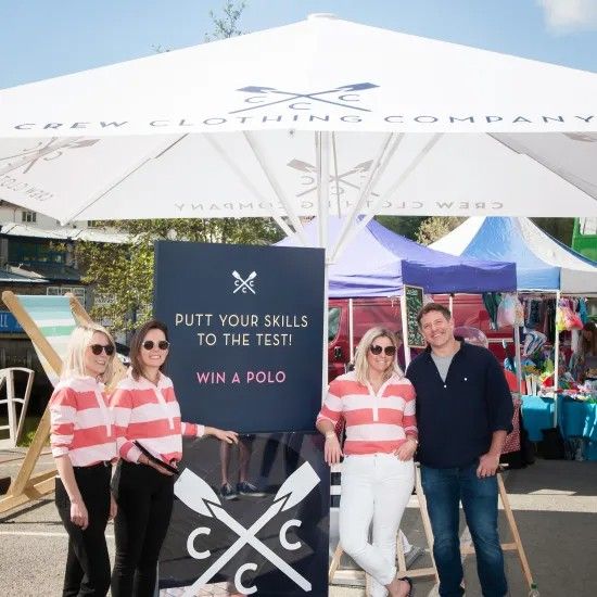 People at a Crew Clothing Company event with sign reading “Putt your skills to the test! Win a polo.”