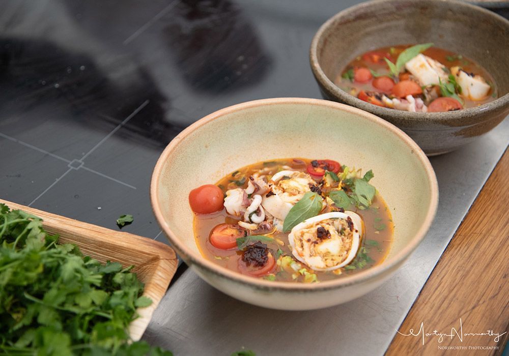 Bowls of seafood soup with tomatoes and herbs.