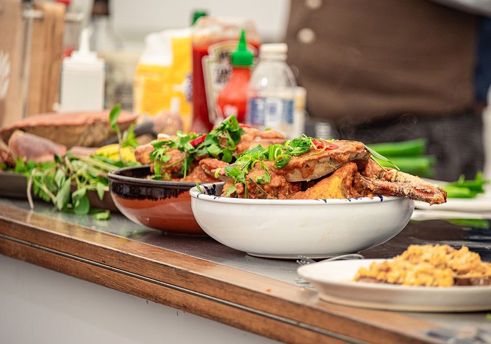 Close-up of a food counter with dishes of various foods and condiments in the background.