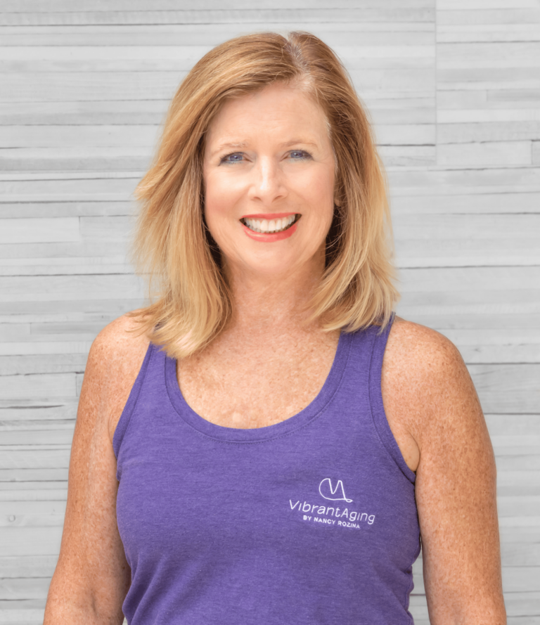 A woman wearing a purple tank top is smiling for the camera.