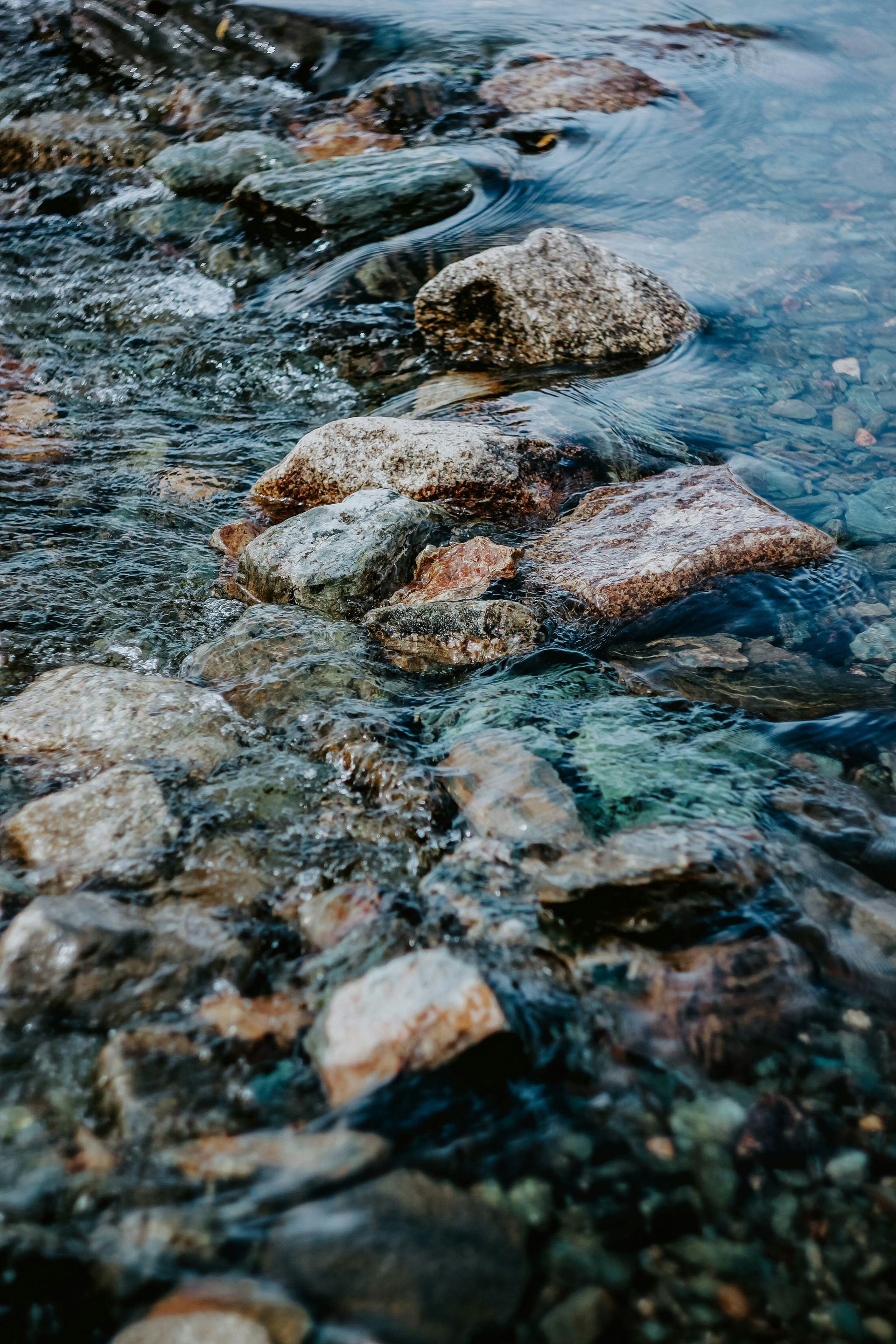 Pebbles and rocks in shallow clear water along a shoreline