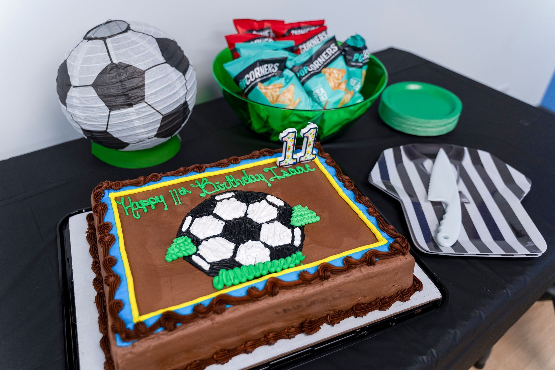 Soccer-themed cake with matching treats and party favors on a table