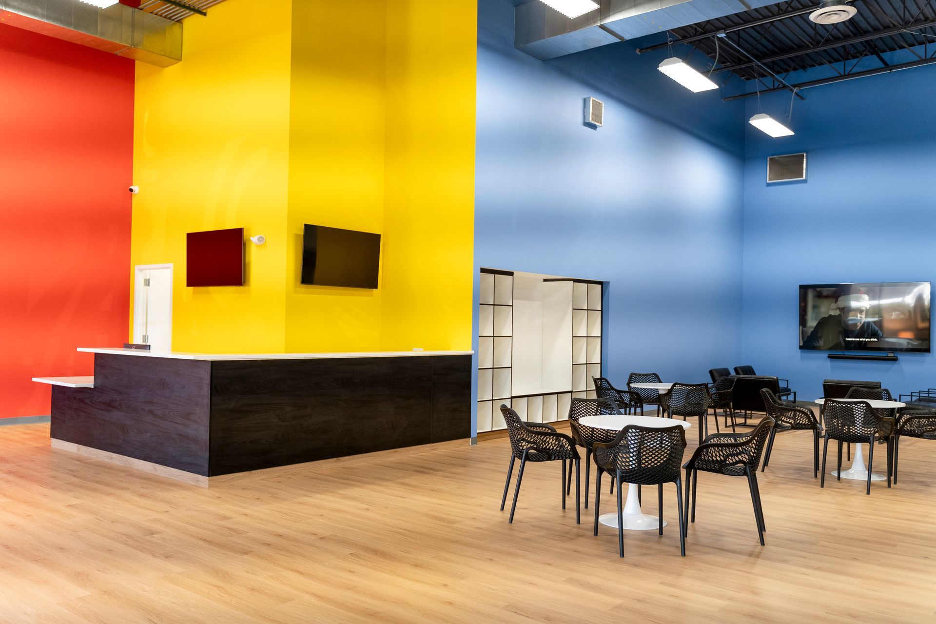 Bright modern office lounge with colorful walls, tables, chairs, and shelving units