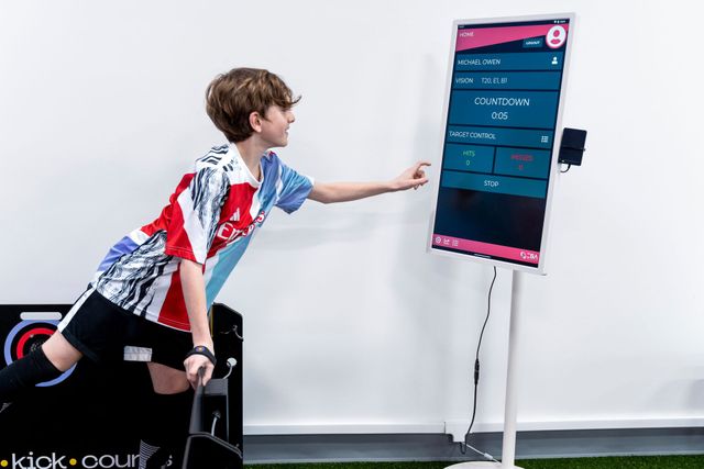 Person reaching toward a tall touchscreen display in a white room