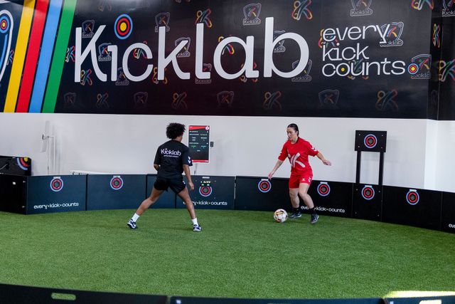 Two players practice soccer drills in a Kicklab indoor training area