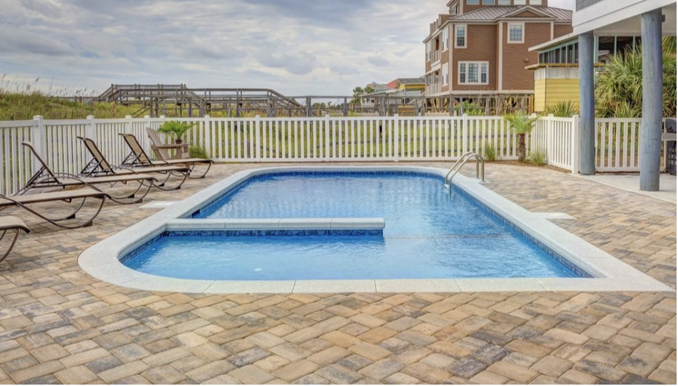 Vinyl pool fence enclosing beautiful in-ground pool.