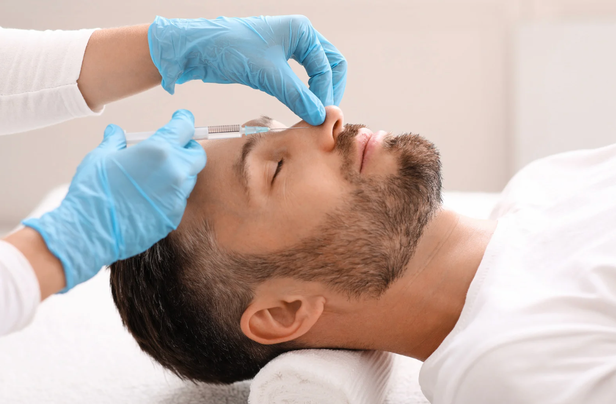 Man receiving a nose injection from gloved hands, lying on a white towel.