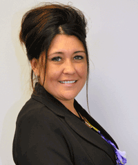 A woman in a black jacket is smiling for the camera