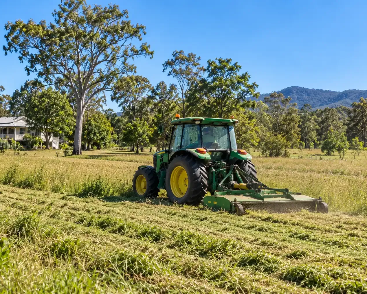 Acreage slashing with a green and yellow tractor and slasher combo on a Townsville acreage.