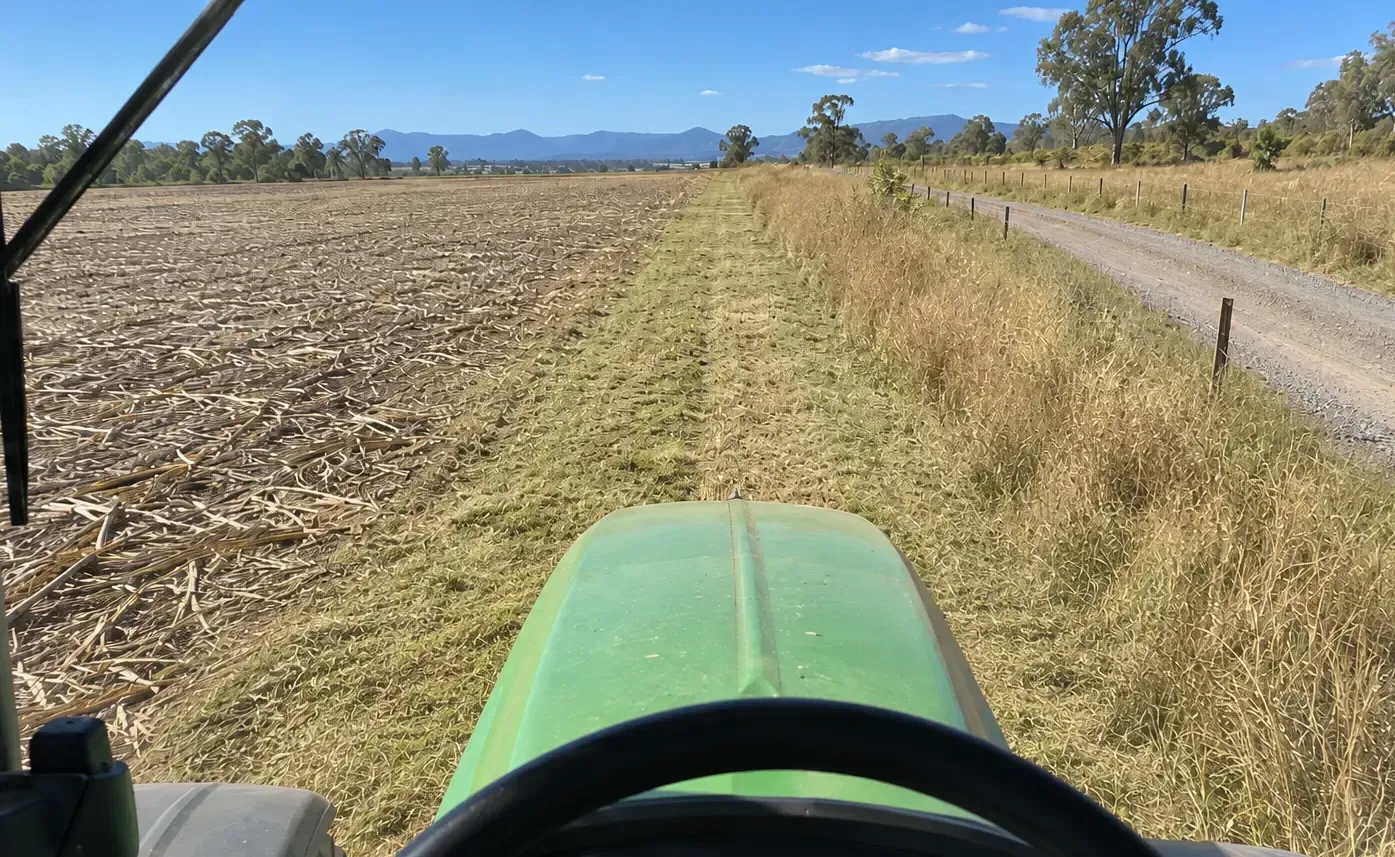 Tractor driver’s view along a freshly slashed firebreak beside a rural Townsville paddock.