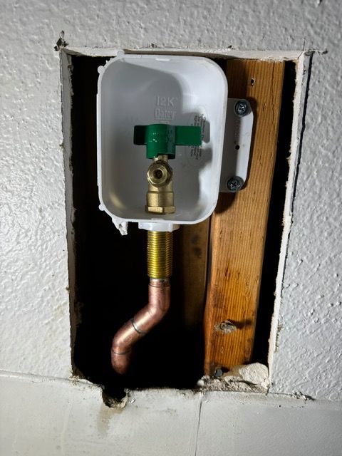 A hole in a wall with a copper pipe coming out of it
