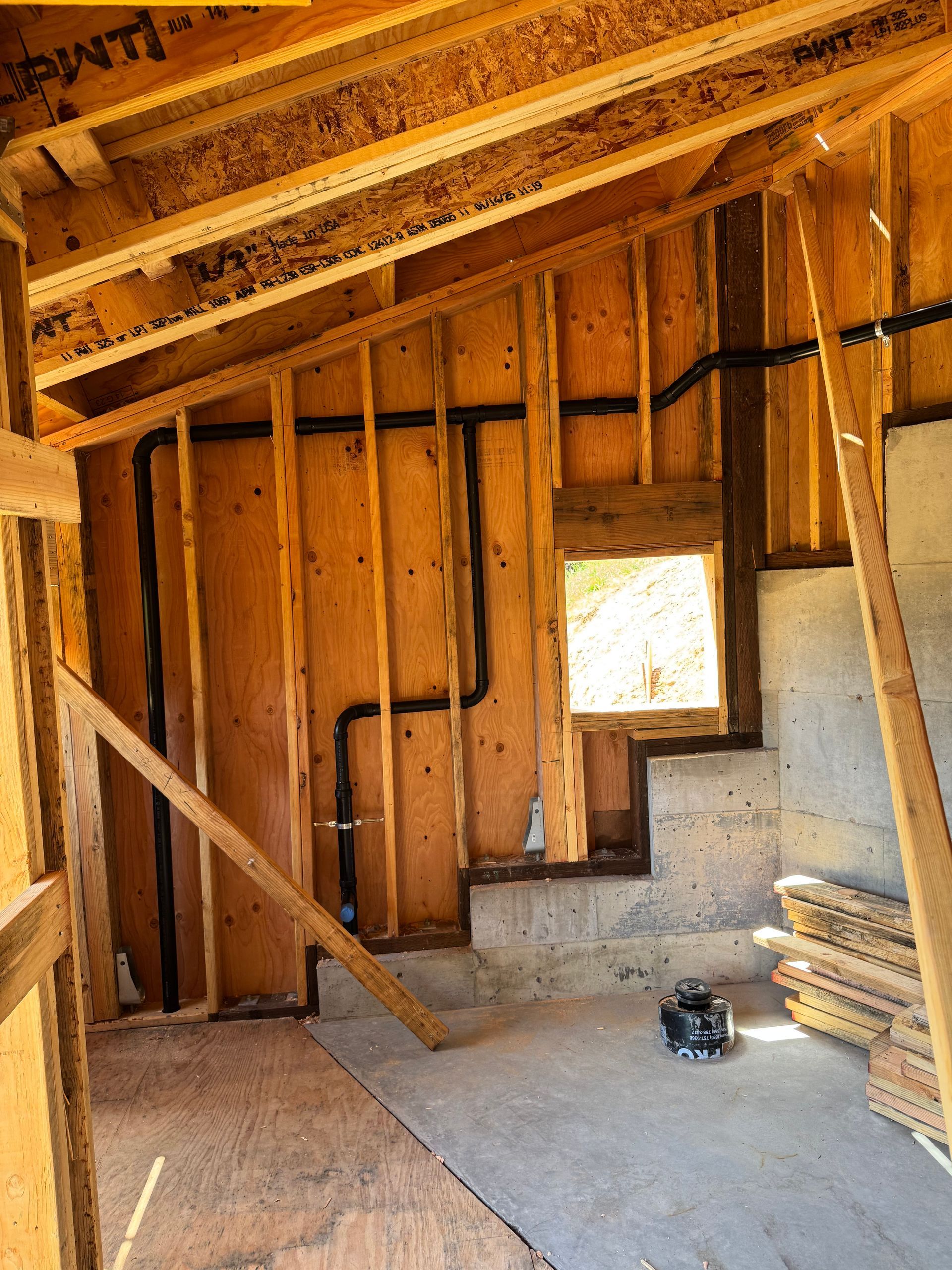 A room under construction with a window and pipes