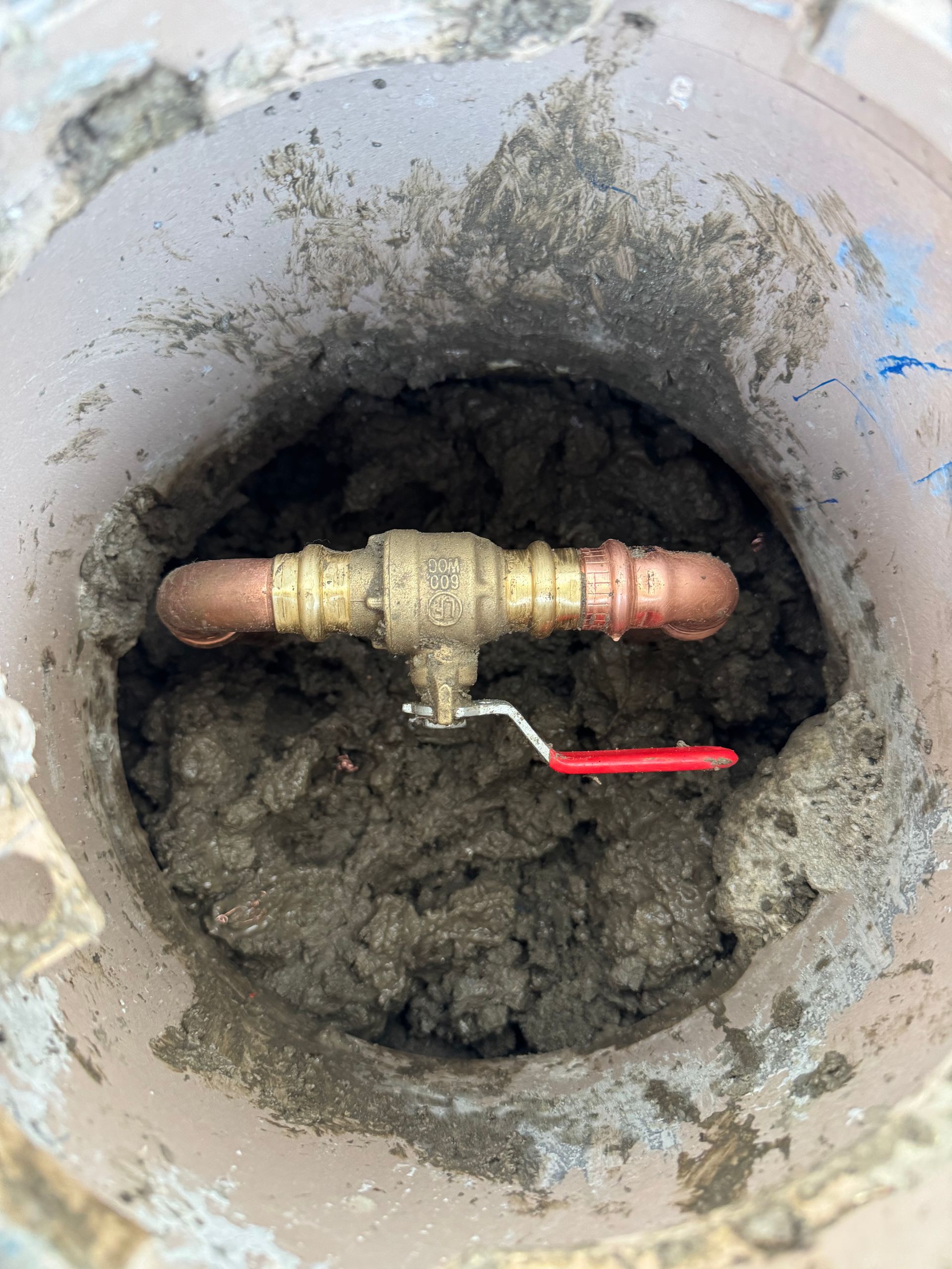 A close up of a copper pipe in a hole in the ground.