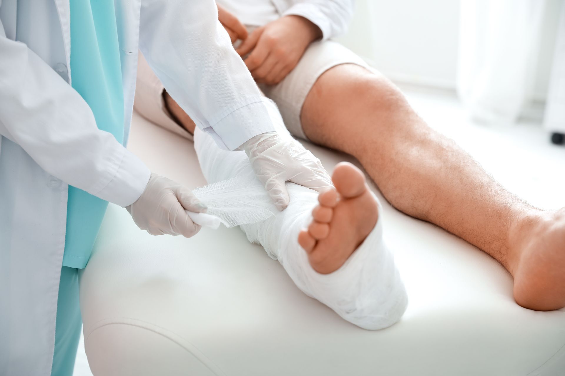 A doctor covers the leg of a patient in plaster, inside a doctor’s office. A doctor covers the leg of a patient in plaster, inside a doctor’s office.