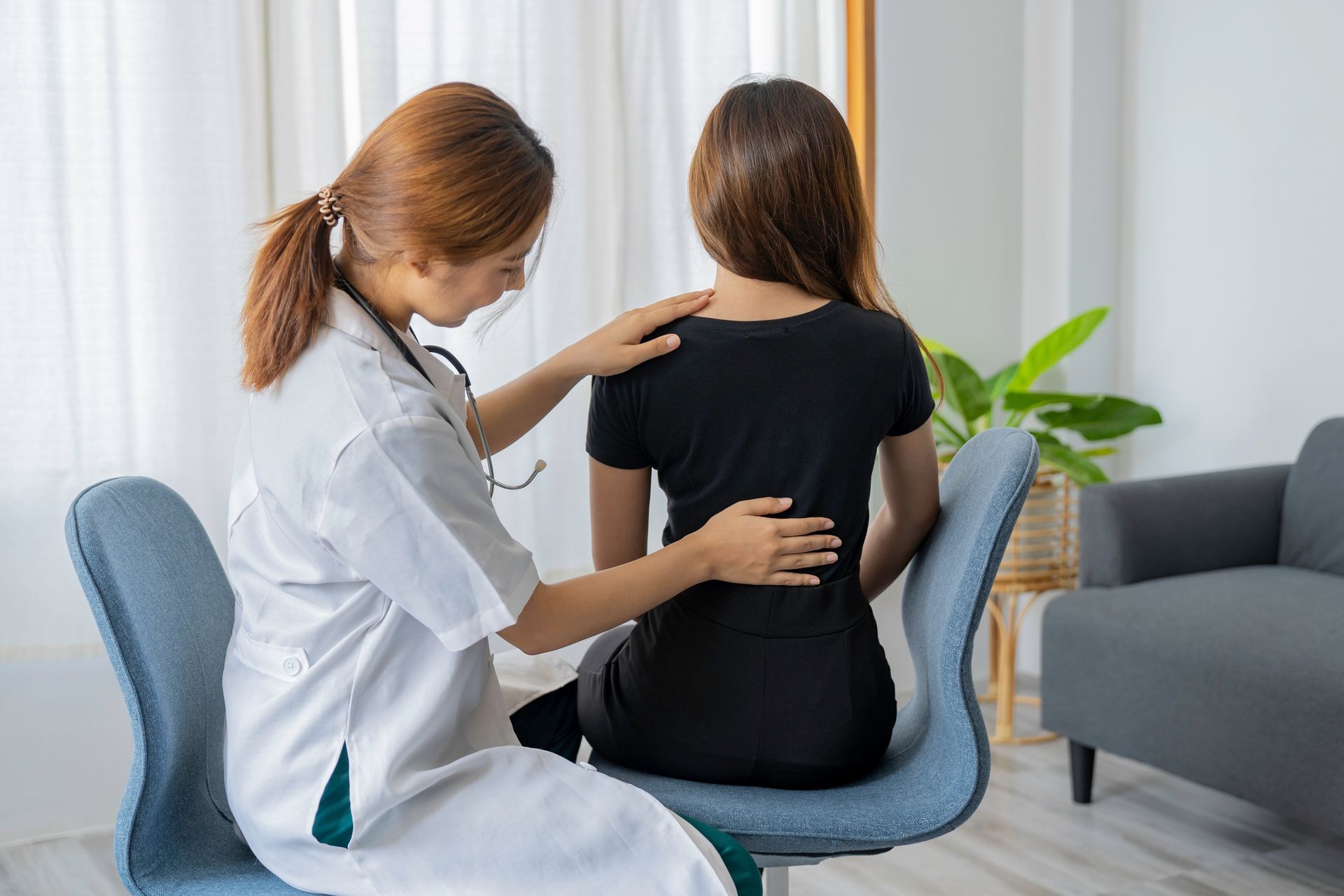 Female doctor doing physiotherapy to treat the back of a female patient. Female doctor doing physiotherapy to treat the back of a female patient.