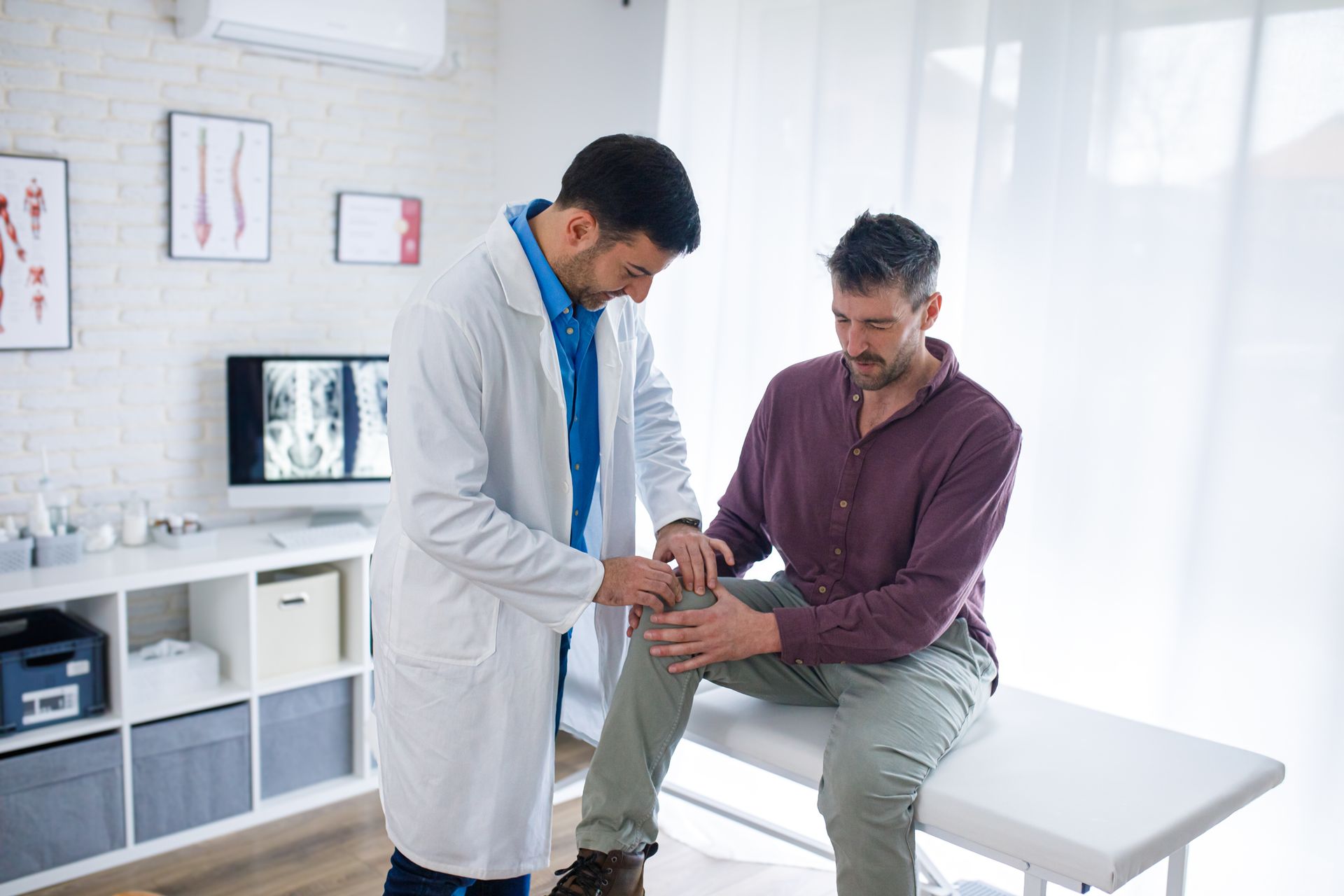 Doctor examining a male patient’s knee, assessing joint pain during an orthopedic clinic visit. Doctor examining a male patient’s knee, assessing joint pain during an orthopedic clinic visit.