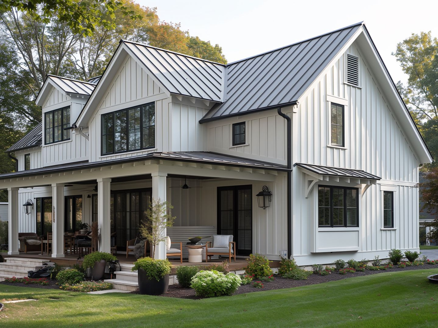 White farmhouse with a porch and black-framed windows, set on a green lawn with a metal roof.