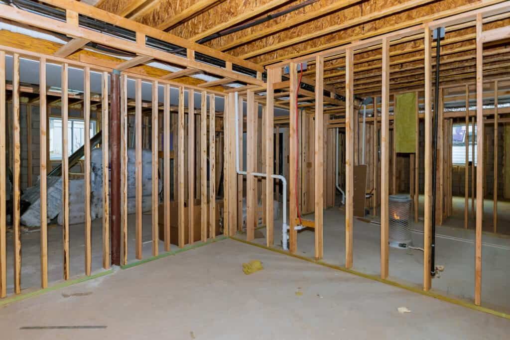 Interior of a room under construction, with wooden studs and exposed framing.