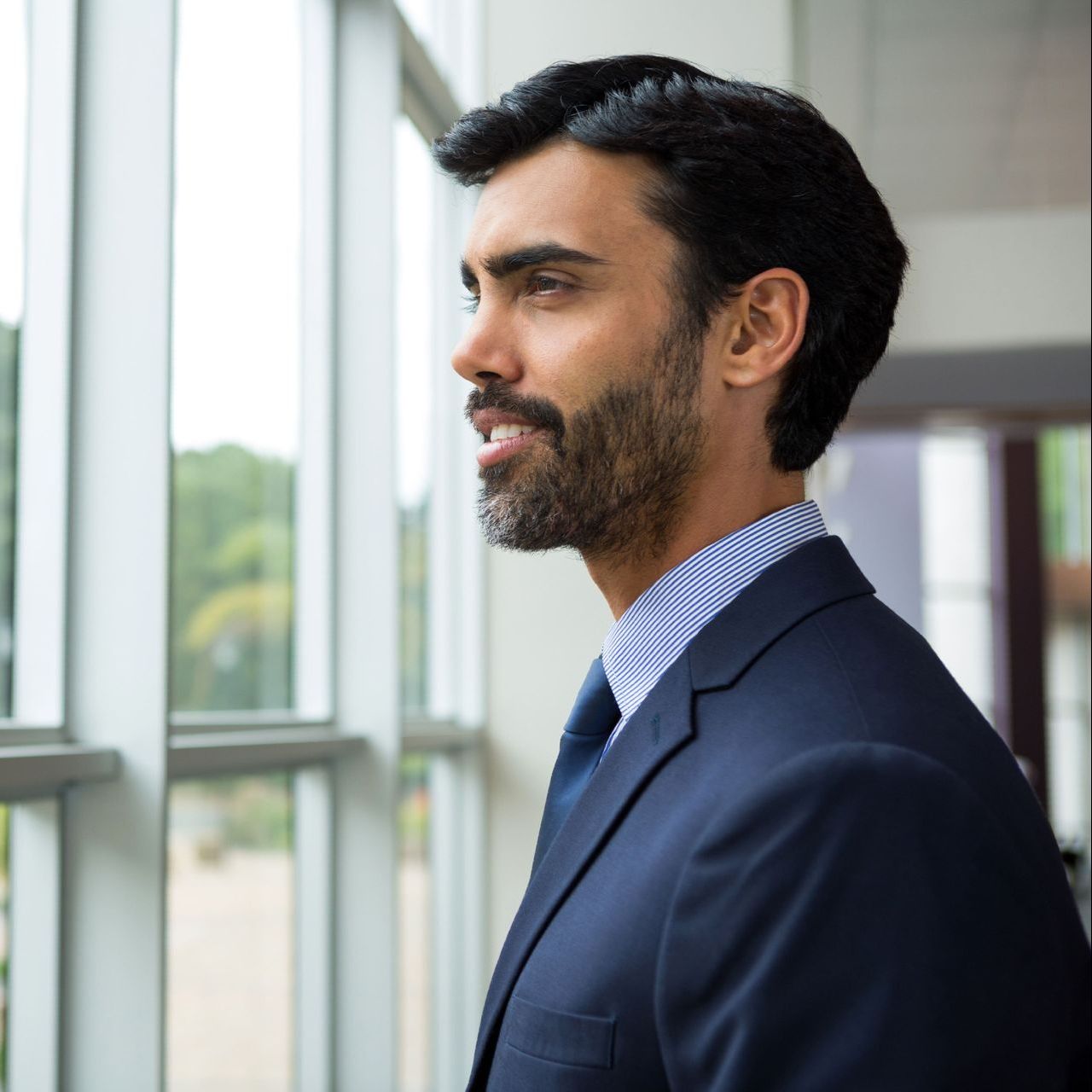 A man with a beard is wearing a green sweater and smiling.