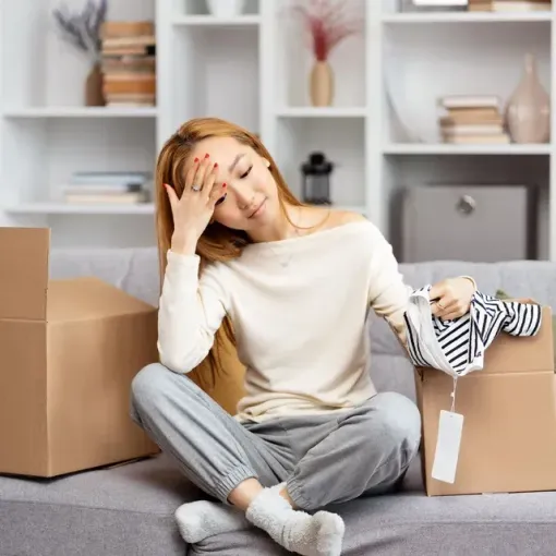 A woman is sitting on a couch holding a pair of shoes