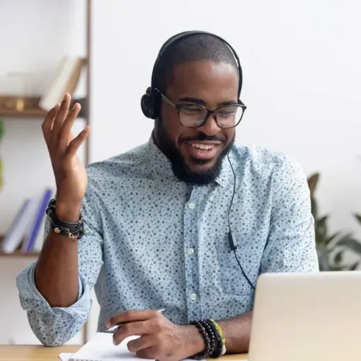 A man wearing headphones is sitting in front of a laptop computer.