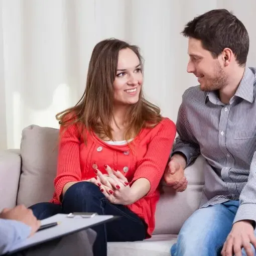 A man and a woman are sitting on a couch talking to each other