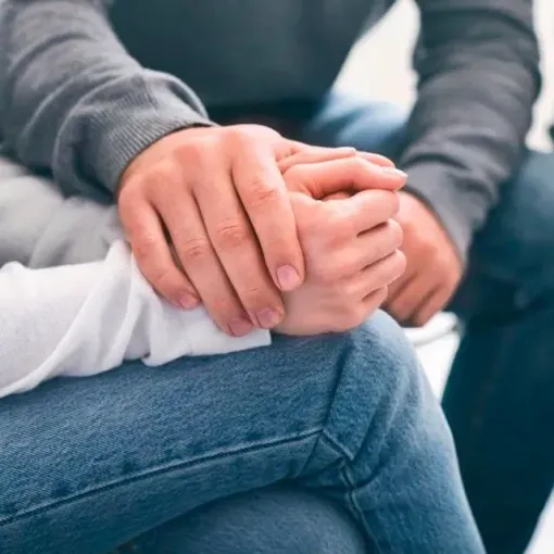 A man is holding a woman 's hand while sitting on her lap.