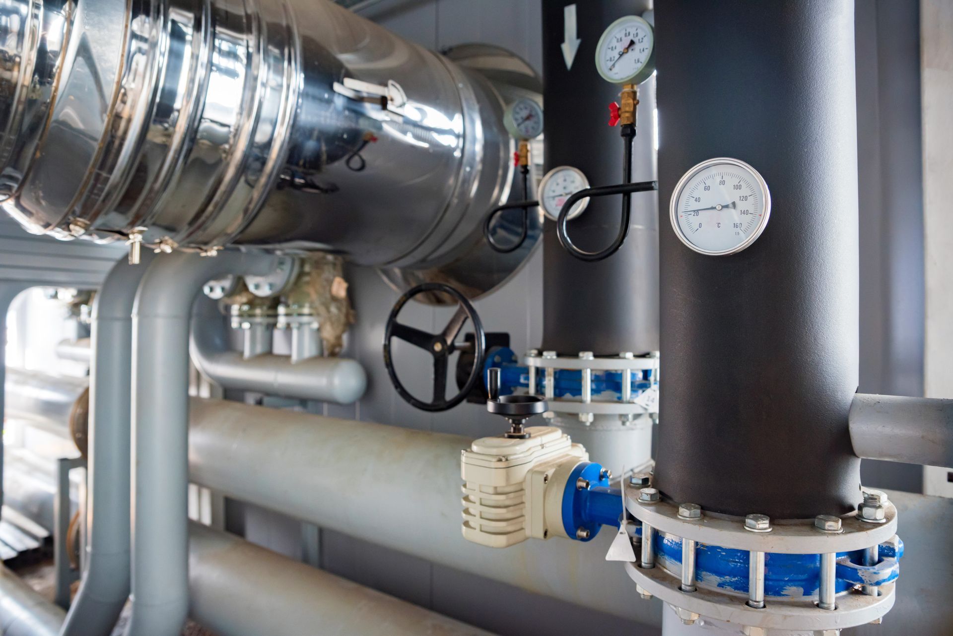 Pipes and gauges in an industrial setting. Silver and black pipes with valves and pressure monitoring. Pipes and gauges in an industrial setting. Silver and black pipes with valves and pressure monitoring.