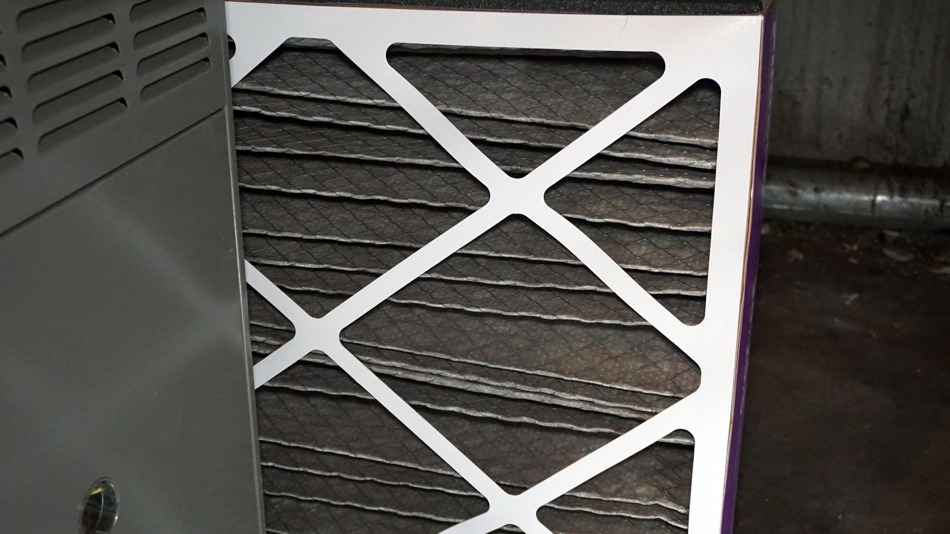 Tan furnace unit with attached ductwork and pipes in a room. Tan furnace unit with attached ductwork and pipes in a room.