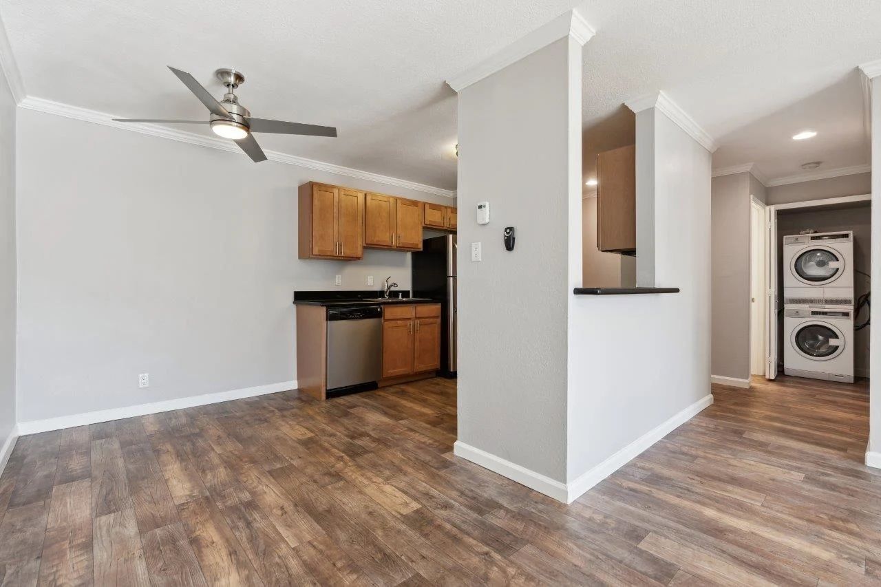 Open-concept apartment: kitchen with wood cabinets, stainless steel appliances, and laundry area.