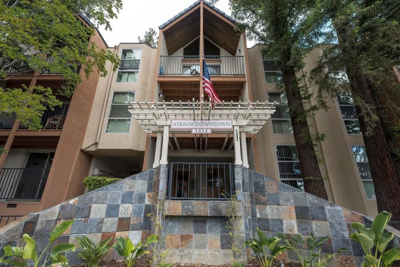 Apartment building entrance with a covered walkway, steps, and an American flag.