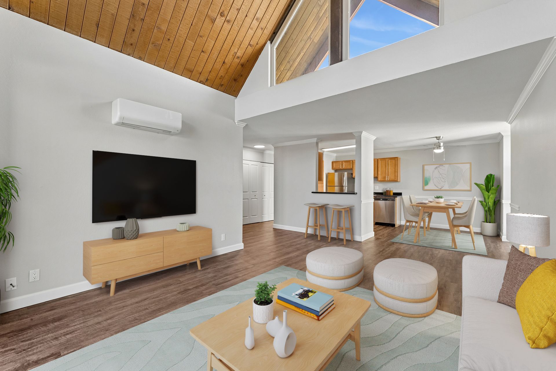 Bright open living room with vaulted wood ceiling, TV, sectional sofa, and dining area