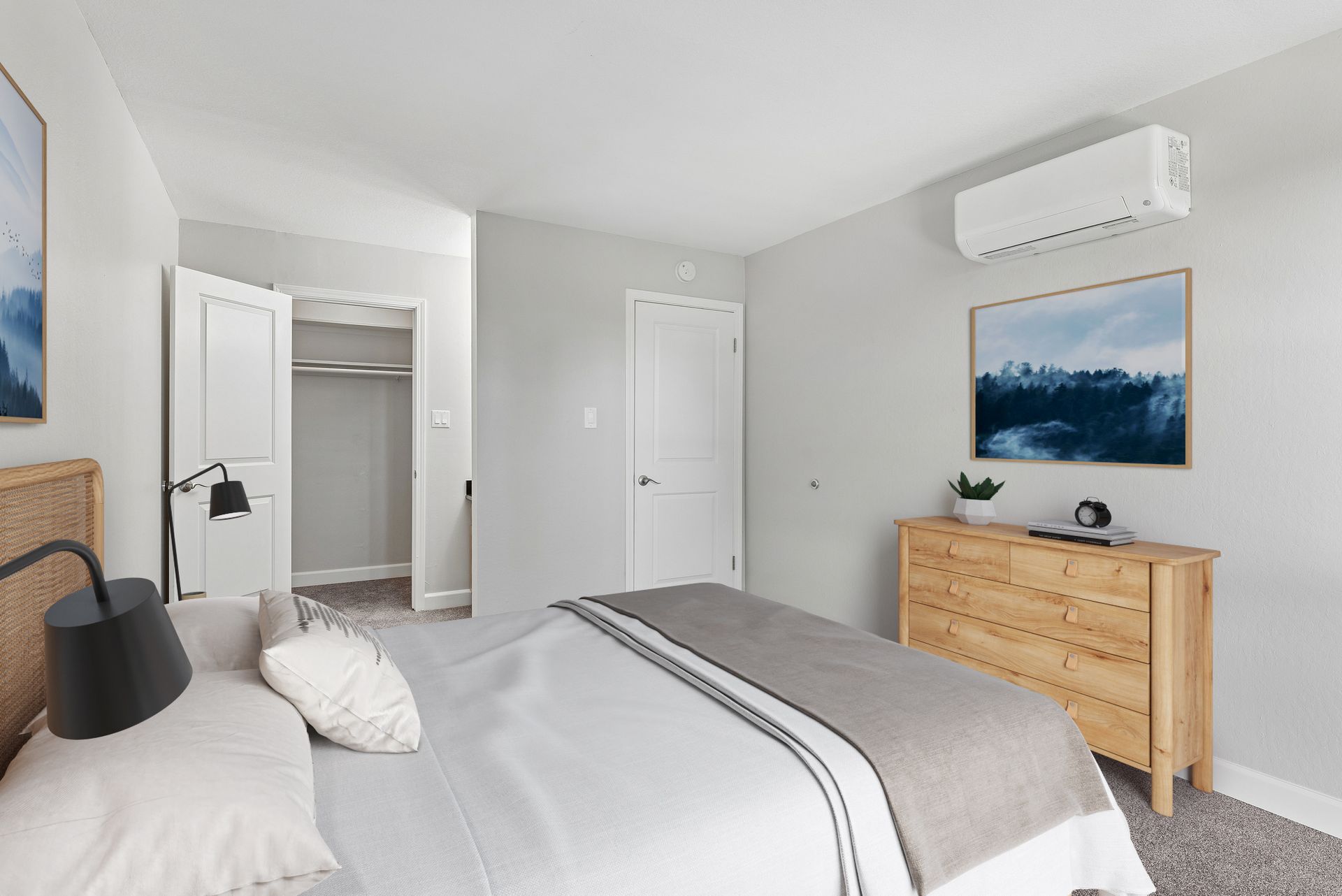 Bright modern bedroom with a bed, dresser, wall art, and air conditioner