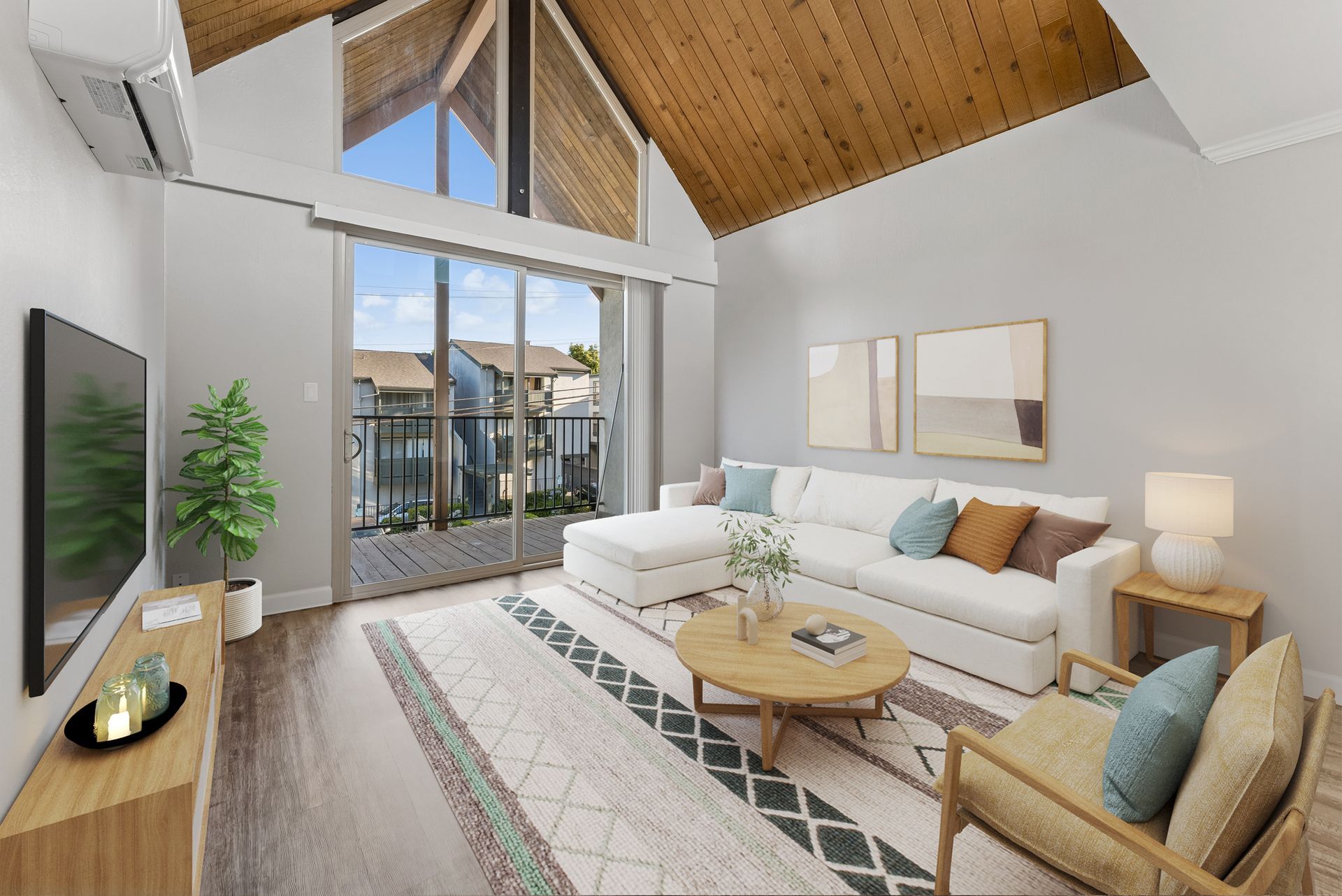 Bright modern living room with vaulted wood ceiling, large windows, white sofa, armchair, and coffee table